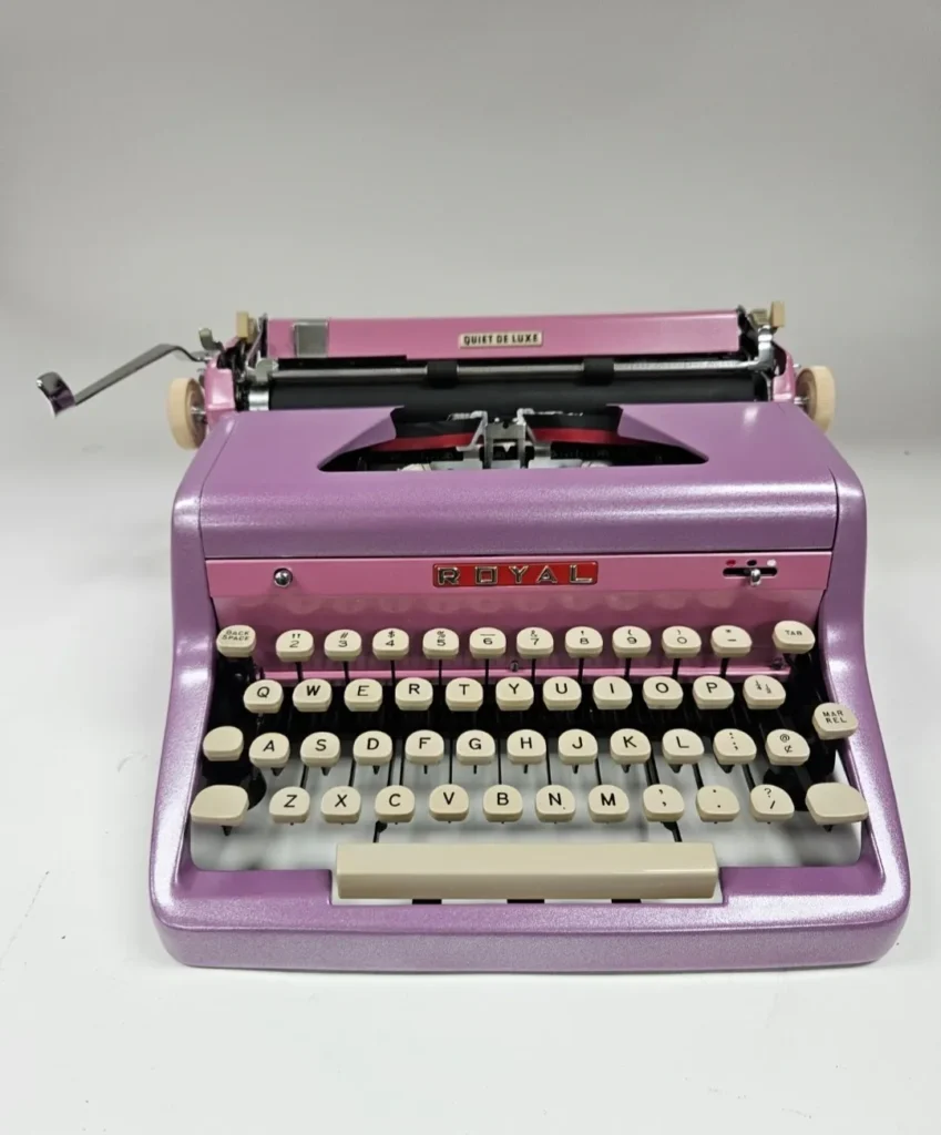 Pink vintage typewriter on white background.